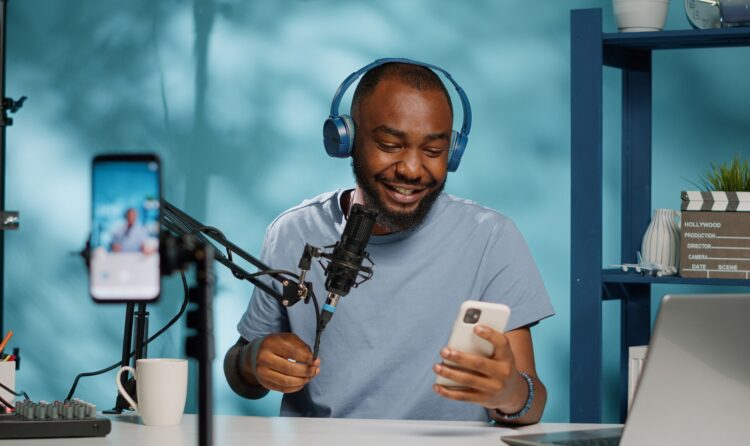 Social media influencer giving good news to subscribers while filming video for vlog channel and holding smartphone. Vlogger using mobile phone camera to record for online podcast.